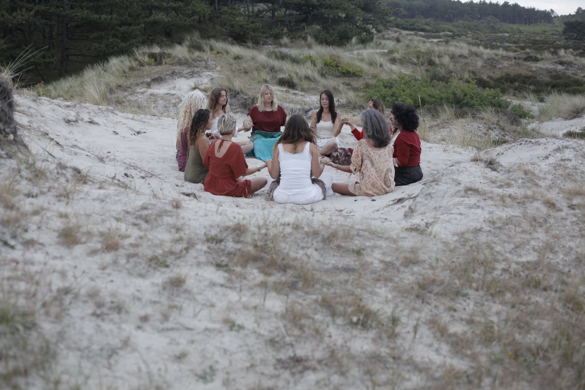 Women sitting in a wide circle among the dunes